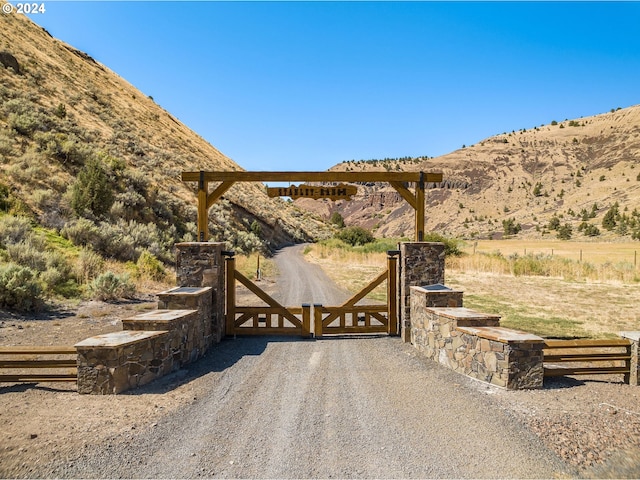 view of gate with a rural view and a mountain view