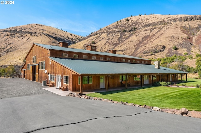 view of front of home featuring a mountain view, a front yard, and cooling unit