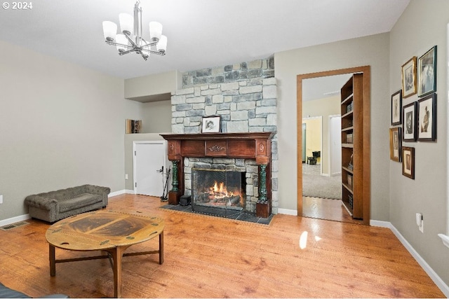 living room featuring an inviting chandelier, a fireplace, and light wood-type flooring