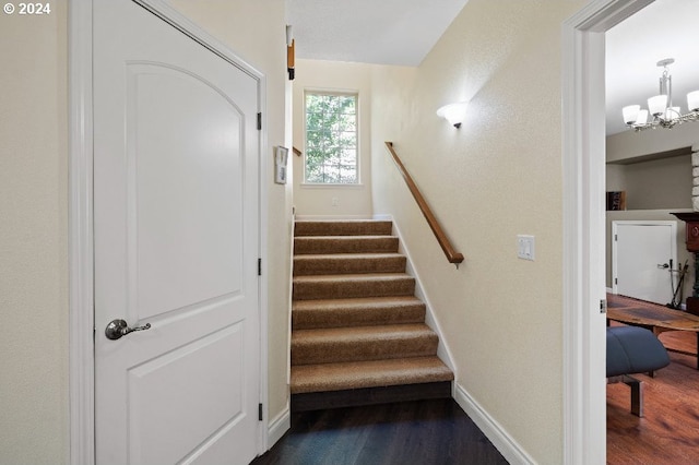 stairs featuring hardwood / wood-style floors and a notable chandelier