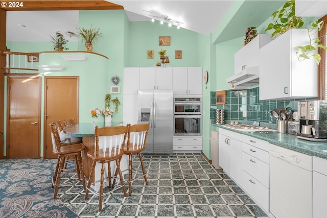 kitchen featuring appliances with stainless steel finishes, white cabinetry, vaulted ceiling, and decorative backsplash