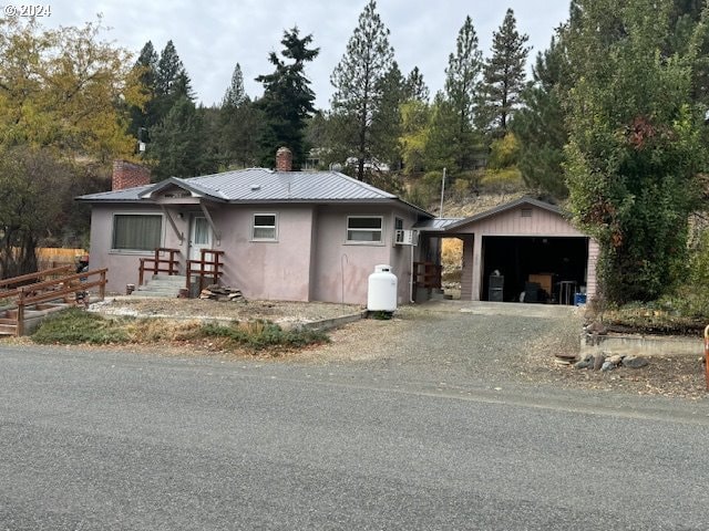 205 N Humbolt St, Canyon City, OR 97820 - view of front facade with an outbuilding, a chimney, metal roof, a garage, and stucco siding