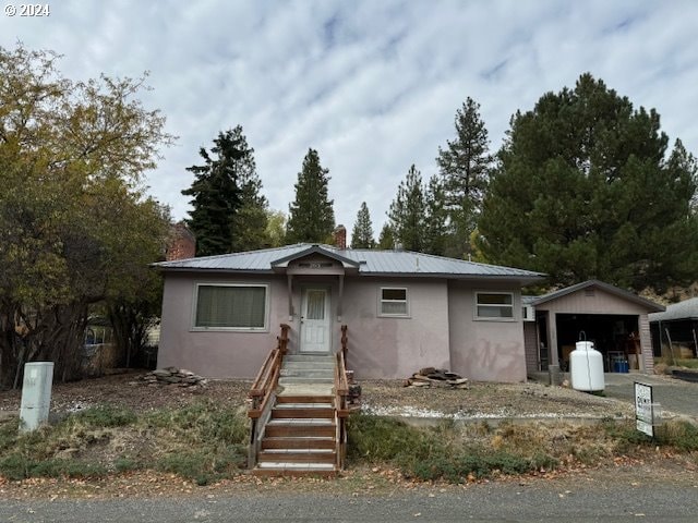 205 N Humbolt St, Canyon City, OR 97820 - view of front of property with stucco siding, a chimney, a detached garage, and metal roof