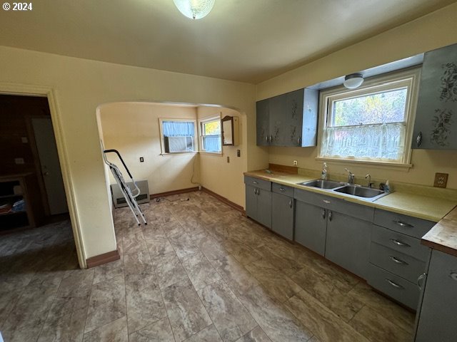 205 N Humbolt St, Canyon City, OR 97820 - kitchen with gray cabinets, arched walkways, a sink, and light countertops