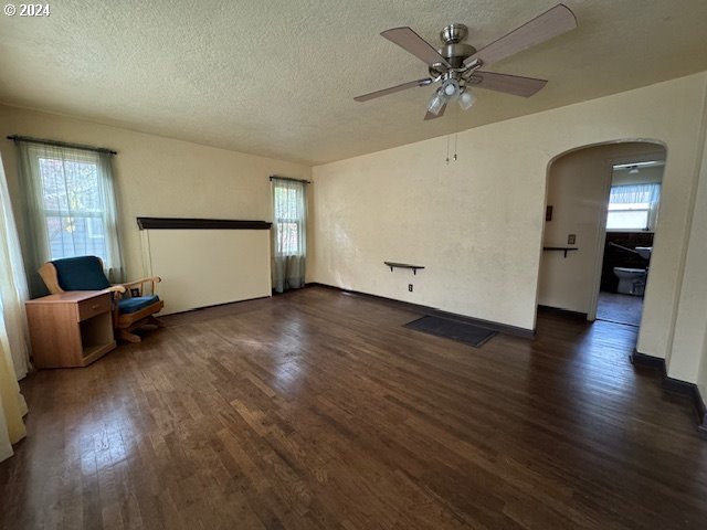 205 N Humbolt St, Canyon City, OR 97820 - empty room featuring a textured ceiling, a ceiling fan, arched walkways, and dark wood-type flooring