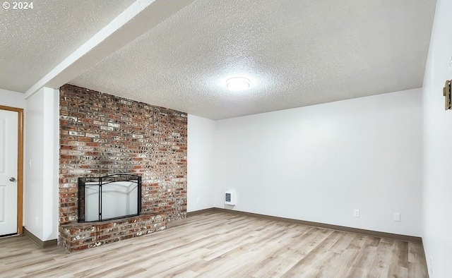 unfurnished living room featuring a brick fireplace, a textured ceiling, and light hardwood / wood-style flooring