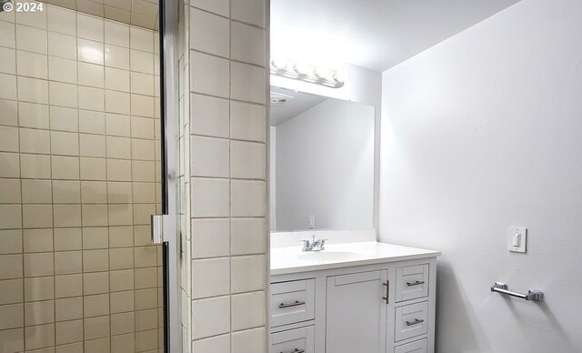 bathroom featuring a shower with door and vanity