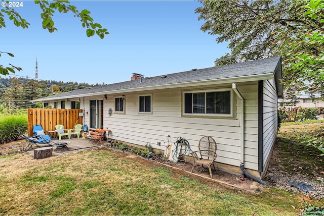 rear view of house with a lawn, an outdoor fire pit, and a patio