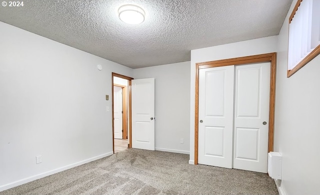 unfurnished bedroom with carpet flooring, a textured ceiling, and a closet