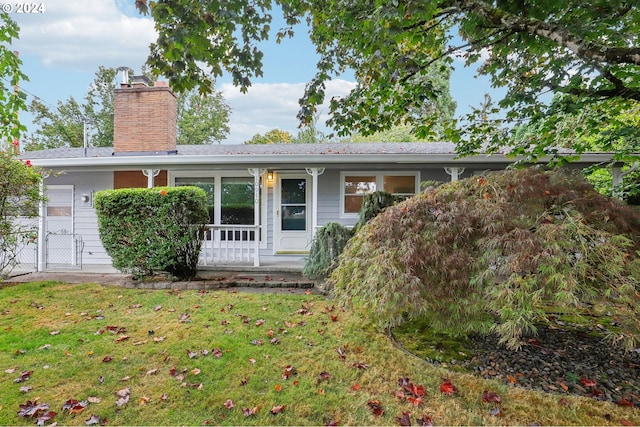 view of front of home with a porch, a chimney, a front yard, and a gate