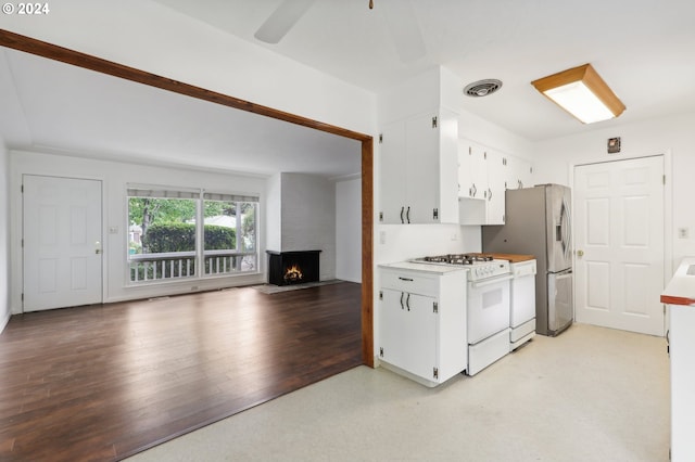 kitchen with ceiling fan, a fireplace, white gas stove, light hardwood / wood-style floors, and white cabinetry