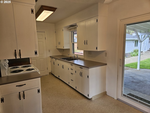 kitchen featuring white cabinets, white electric range, dark countertops, and a sink