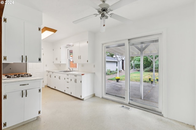 kitchen featuring white cabinets, stainless steel gas stovetop, ceiling fan, and sink