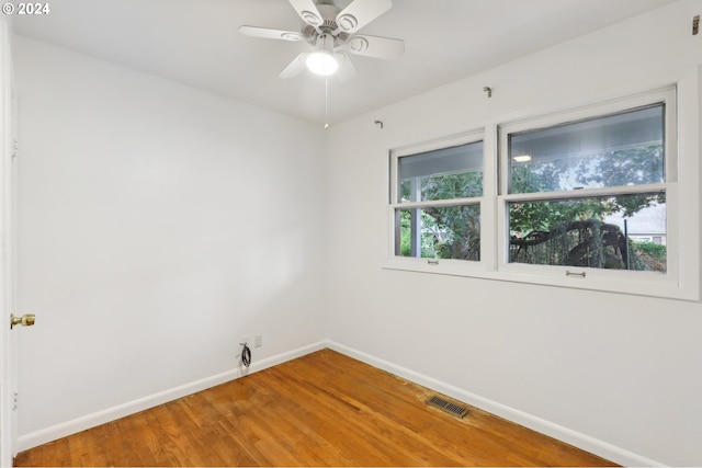 spare room featuring a ceiling fan, visible vents, wood finished floors, and baseboards