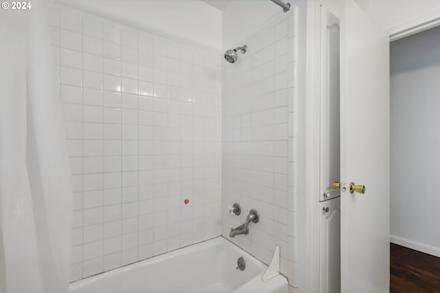 full bathroom with washtub / shower combination, wood finished floors, and baseboards