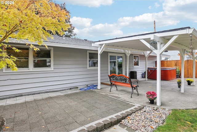 back of house featuring fence, roof with shingles, a patio area, and a hot tub
