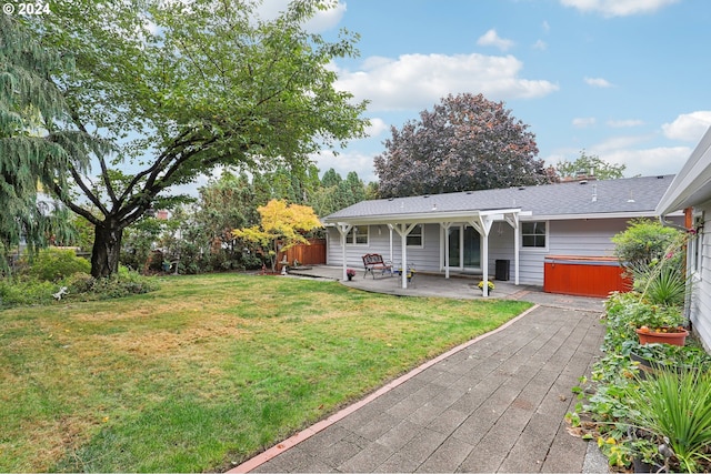 view of front facade with a front yard, a hot tub, and a patio area