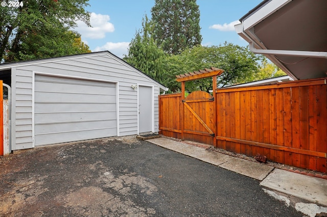detached garage featuring fence, a gate, and aphalt driveway