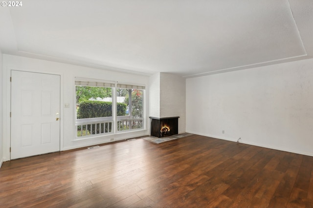 unfurnished living room featuring a brick fireplace, hardwood / wood-style floors, and visible vents