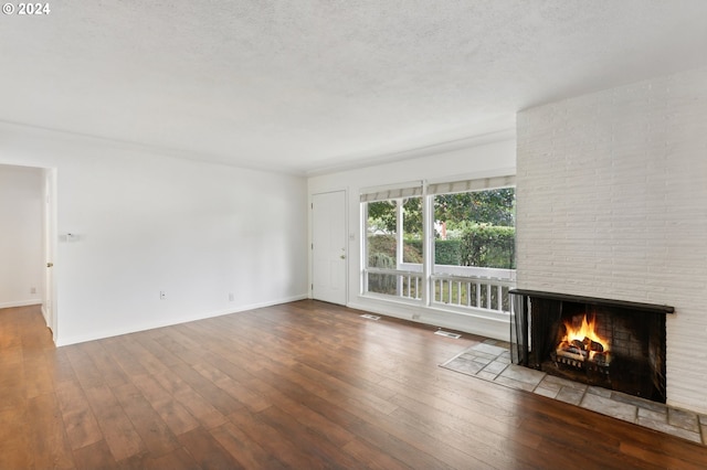 unfurnished living room with a textured ceiling, wood-type flooring, and a fireplace