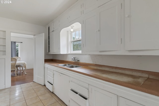 kitchen featuring light tile patterned floors, a wealth of natural light, sink, and white cabinets