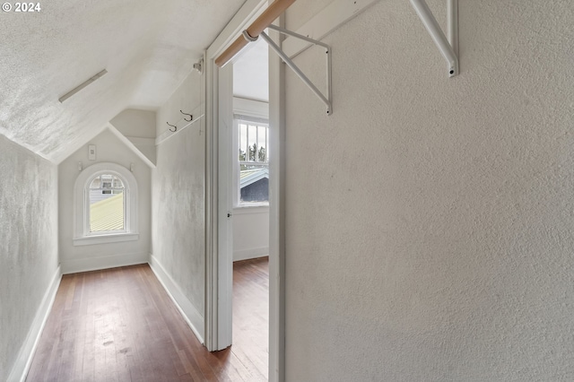 interior space with a textured ceiling, vaulted ceiling, and hardwood / wood-style floors