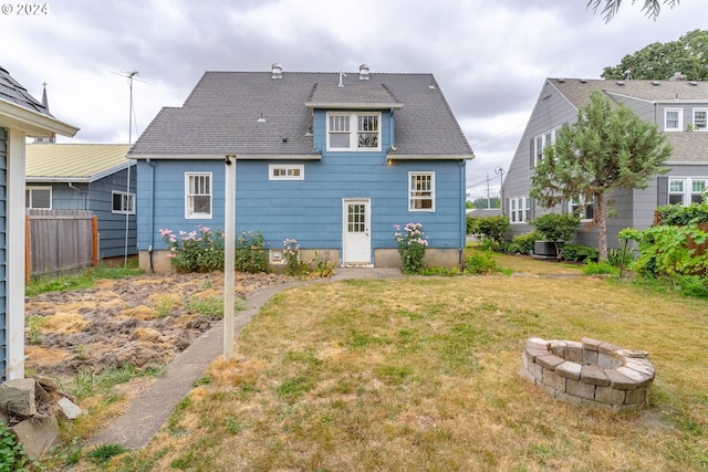 back of property featuring an outdoor fire pit and a yard