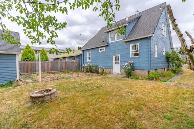 rear view of property with a fire pit and a lawn