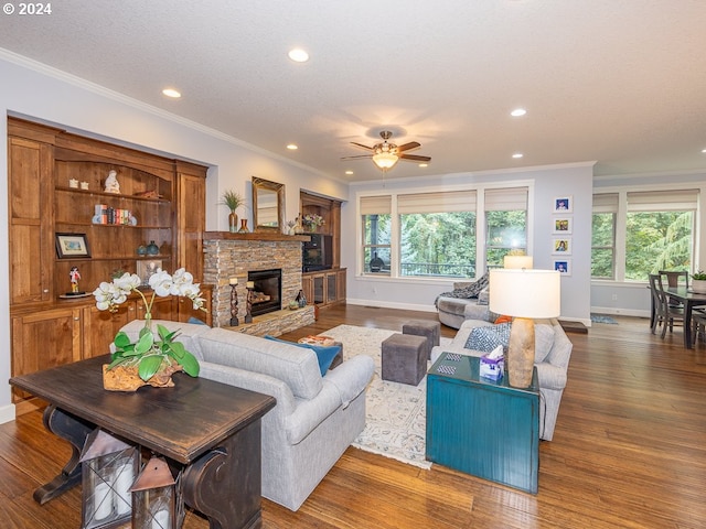 living room featuring a fireplace, ceiling fan, ornamental molding, and dark wood-type flooring