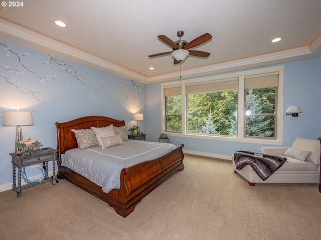 bedroom featuring ornamental molding, a textured ceiling, light colored carpet, a tray ceiling, and ceiling fan