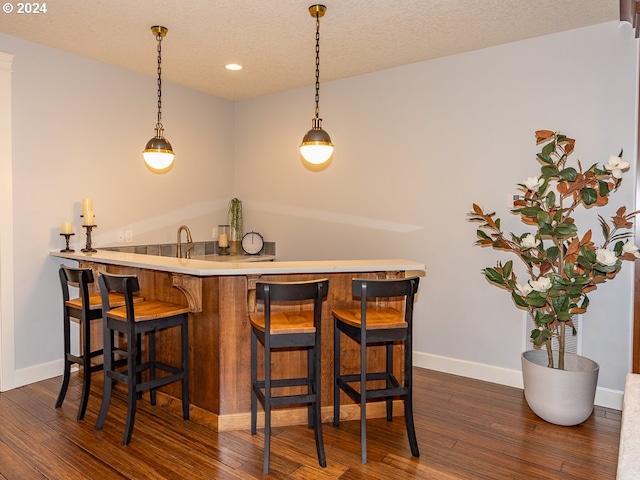 bar with pendant lighting, dark hardwood / wood-style floors, and a textured ceiling