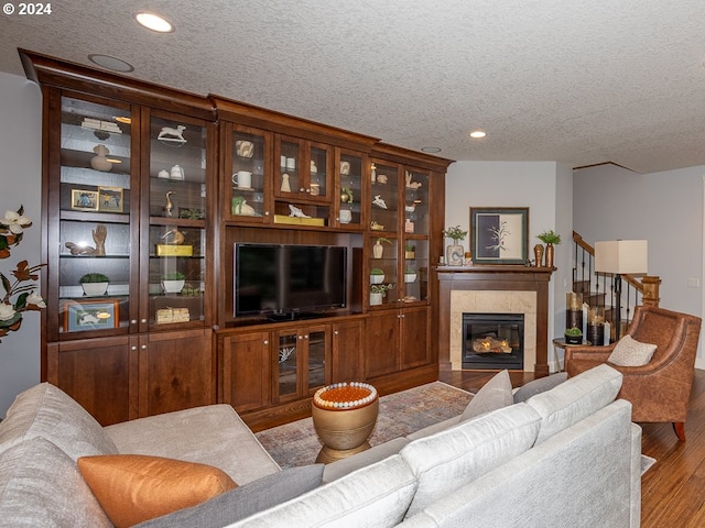 living room featuring a tile fireplace, hardwood / wood-style floors, and a textured ceiling