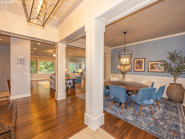 dining space with wood-type flooring, crown molding, and decorative columns