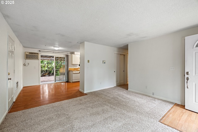 3314 SE 85th Ave, Portland, OR 97266 - unfurnished living room featuring carpet floors, a textured ceiling, baseboards, wood finished floors, and a wall mounted air conditioner