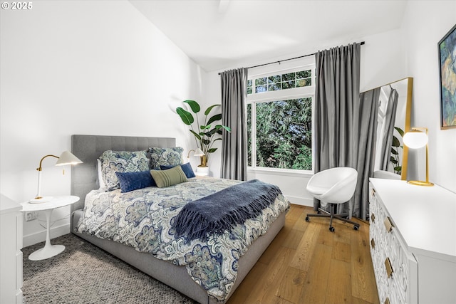 bedroom with wood-type flooring, vaulted ceiling, and baseboards