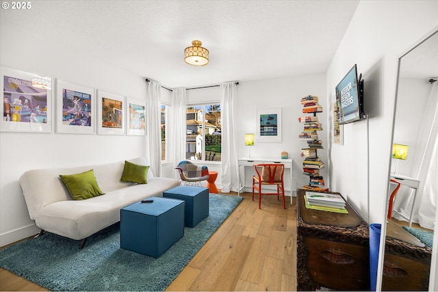 sitting room with light wood-style flooring, baseboards, and a textured ceiling