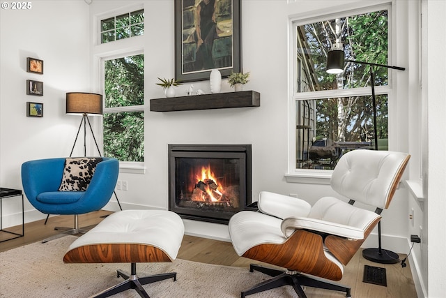 living area with a lit fireplace, wood finished floors, and baseboards