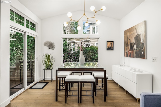 dining space with vaulted ceiling, plenty of natural light, wood-type flooring, and a notable chandelier