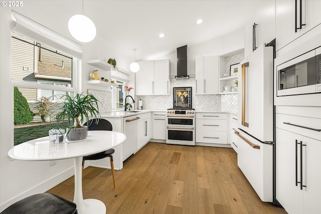 kitchen with white appliances, tasteful backsplash, wall chimney range hood, open shelves, and a sink