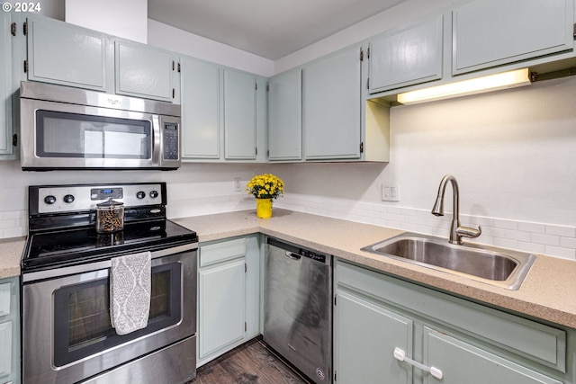 kitchen featuring appliances with stainless steel finishes, sink, and dark hardwood / wood-style flooring