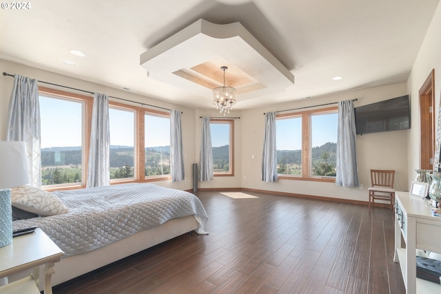 bedroom featuring a tray ceiling, dark hardwood / wood-style floors, and an inviting chandelier