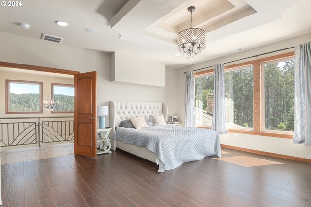 bedroom with a tray ceiling, dark hardwood / wood-style flooring, and a notable chandelier