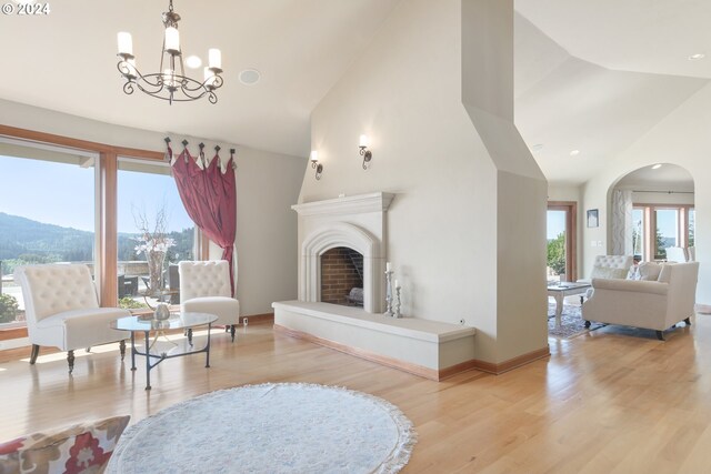 living room featuring light wood-type flooring, high vaulted ceiling, a mountain view, and a chandelier