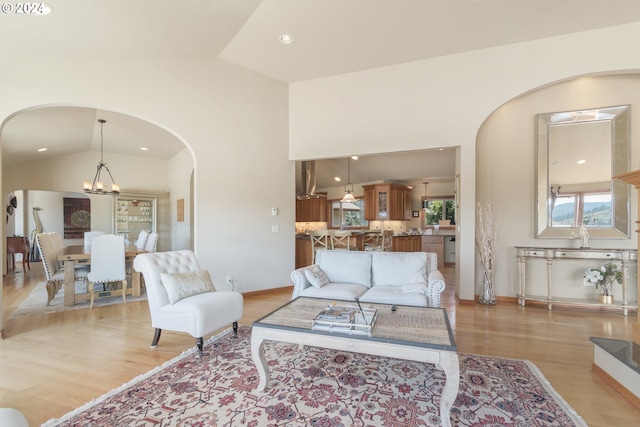 living room with lofted ceiling, a notable chandelier, and light hardwood / wood-style floors