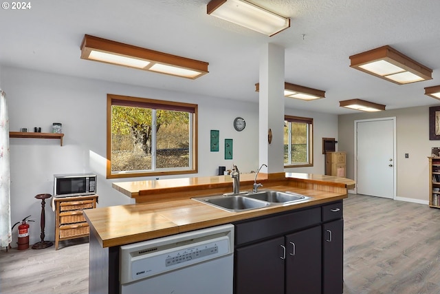 kitchen with sink, plenty of natural light, wooden counters, and dishwasher