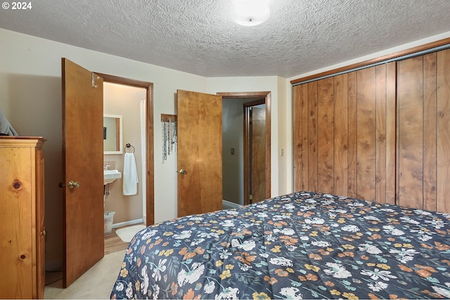 carpeted bedroom featuring connected bathroom, a closet, and a textured ceiling