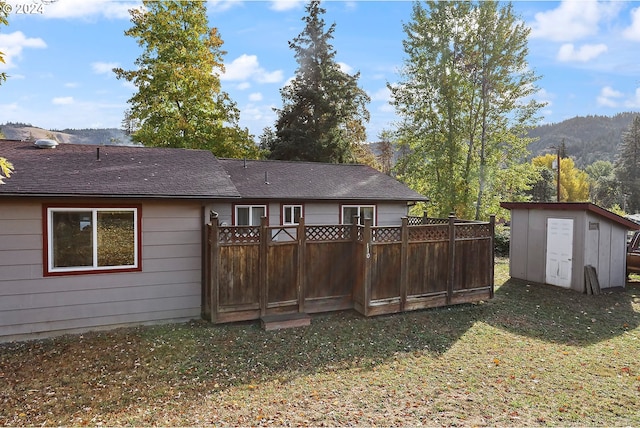 rear view of property featuring a storage shed, a yard, and a mountain view