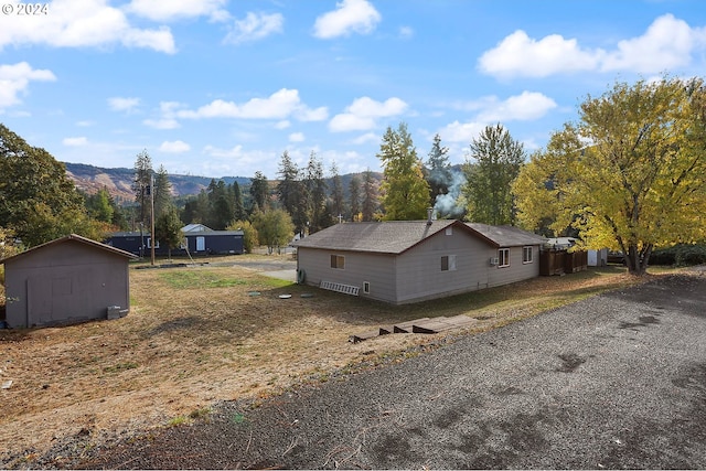 view of side of home featuring a mountain view and a storage unit