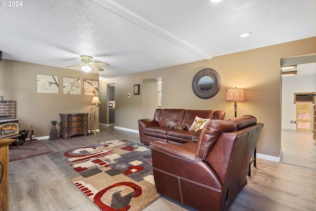 living room with hardwood / wood-style floors, a wood stove, a textured ceiling, and ceiling fan