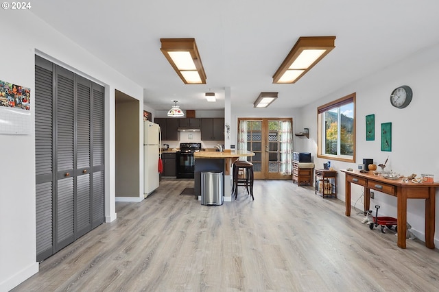 kitchen featuring sink, light hardwood / wood-style flooring, a breakfast bar, black / electric stove, and white fridge